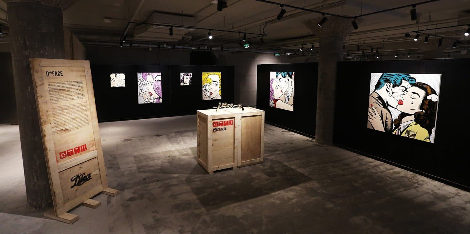 D*Face wall of pop paintings with wall-label crate stands