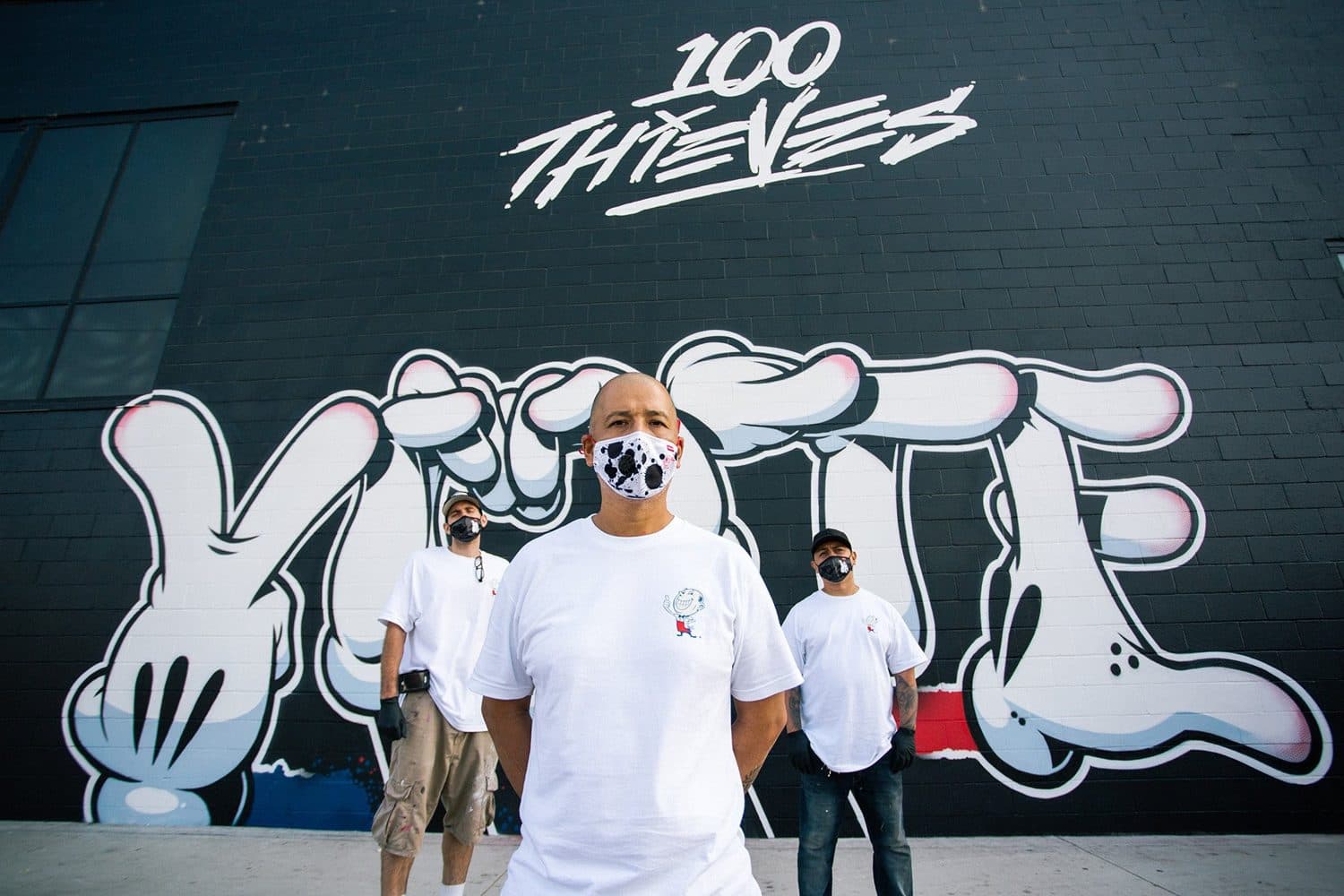 OG Slick, masked, in front of the completed mural.