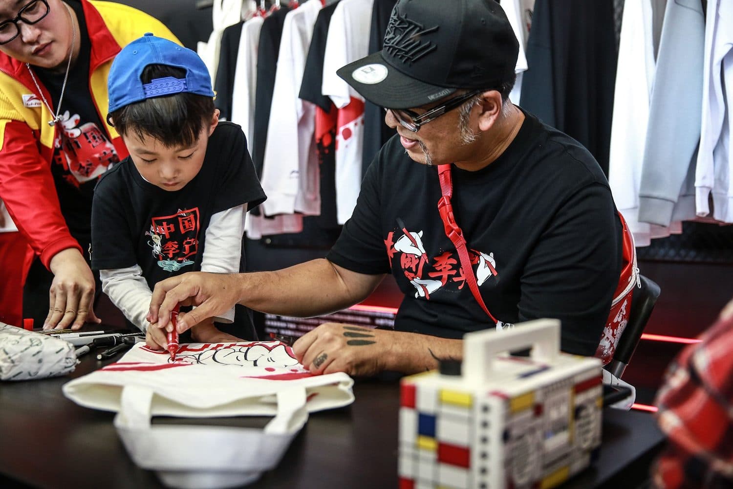Slick signs a tote for a young fan at the Beijing Sanlitun pop-up.