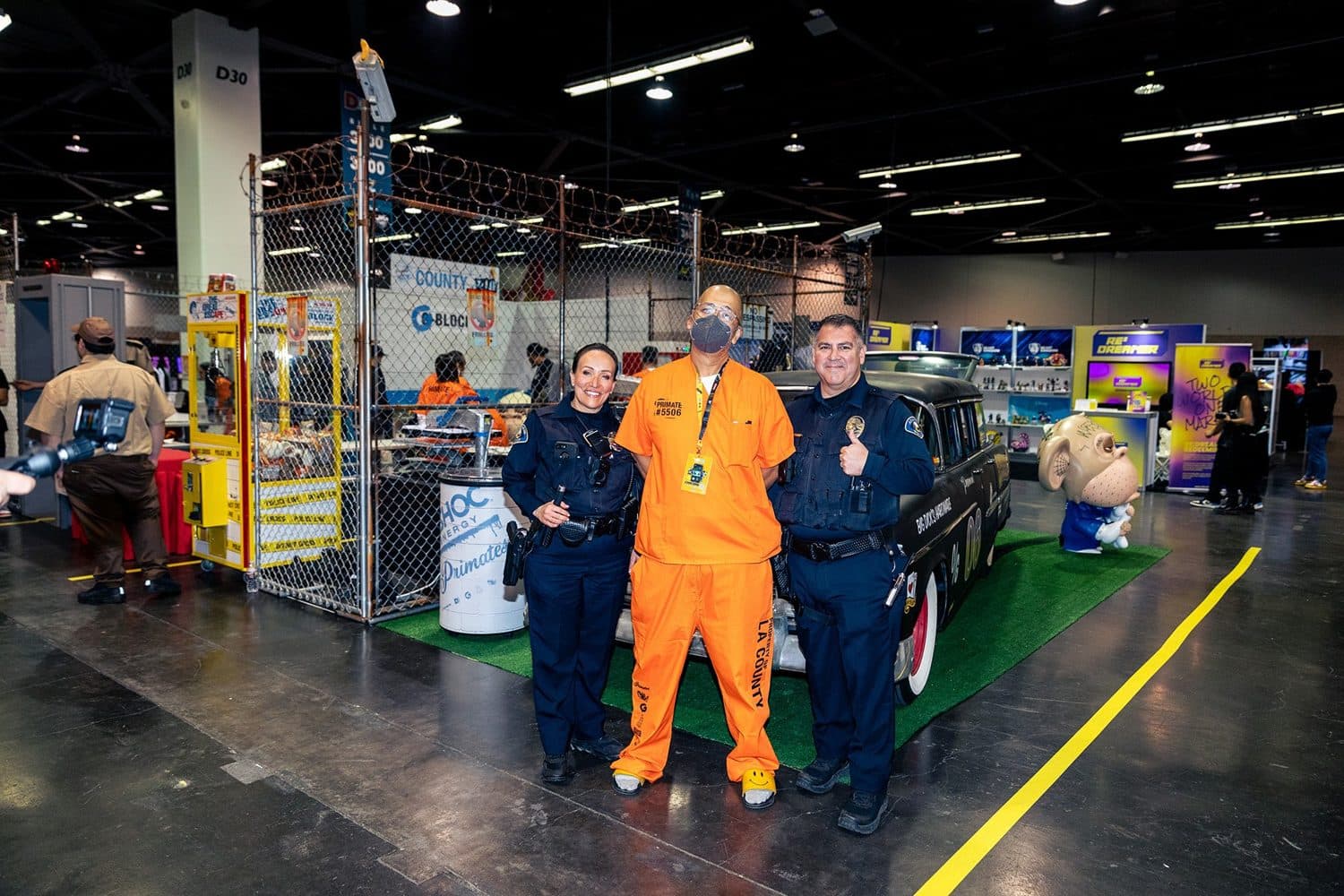 OG Slick, in a numbered jumpsuit, with costumed officers at the booth.